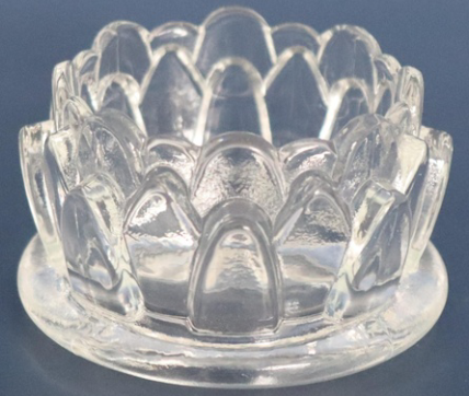 A glass tea candle holder in the shape of a lotus flower