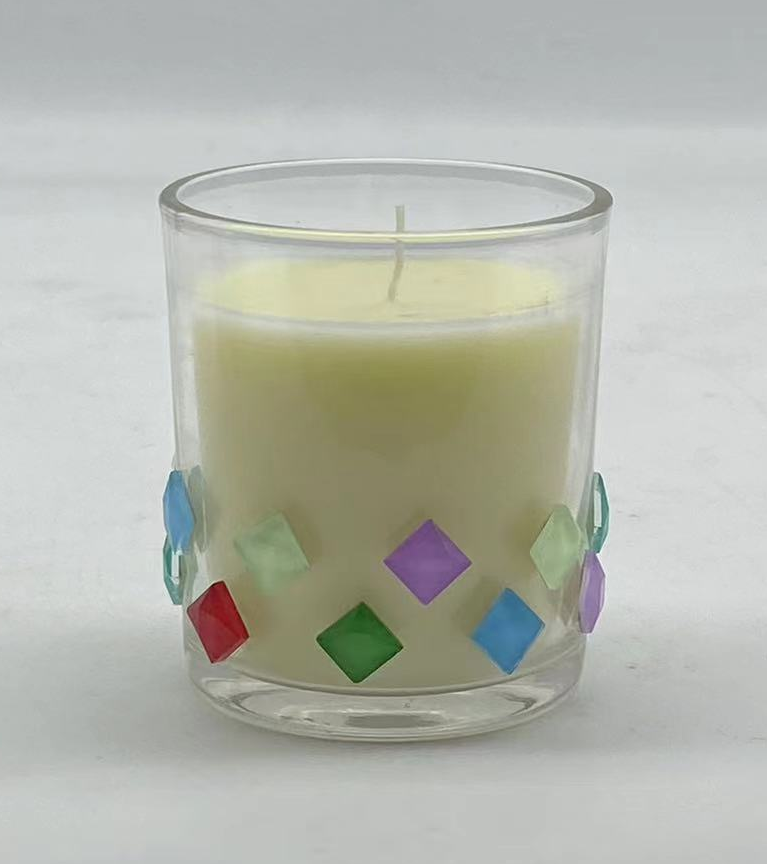 A cylindrical glass votive candle holder with diamond-shaped sequins